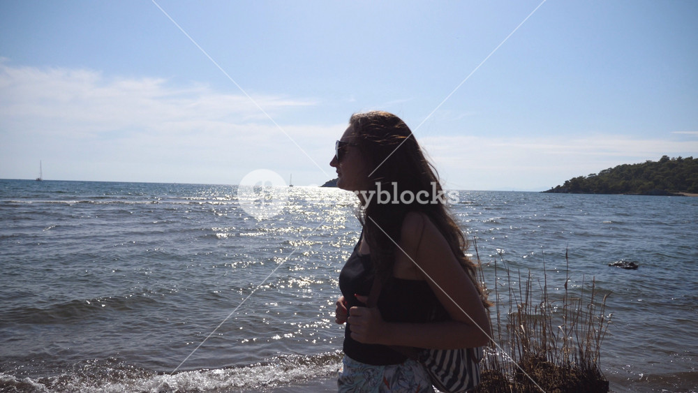 Female tourist walking at beautiful ocean beach. Young traveler woman with backpack going on sea shore. Girl hiker stepping at seaside during travel or summer vacation. Slow motion Close up.