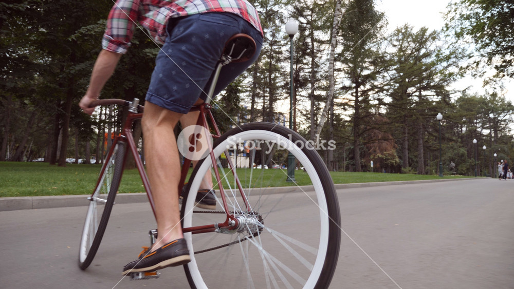 Young man riding a vintage bicycle at the park road. Sporty guy cycling outdoor. Healthy active lifestyle. Low angle of view Close up Slow motion.