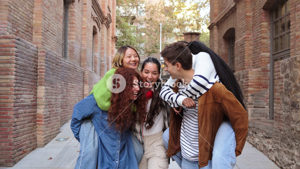 Group of male students giving a piggyback ride to her female friends, walking or running to the Excited multiracial enjoying together at the