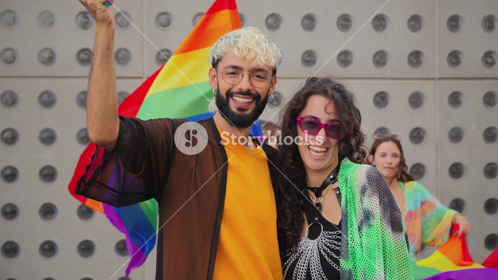 Gay young man and lesbian woman celebrating the lgbt pride with their friends, waving the rainbow flag and havin fun together. Real diverse