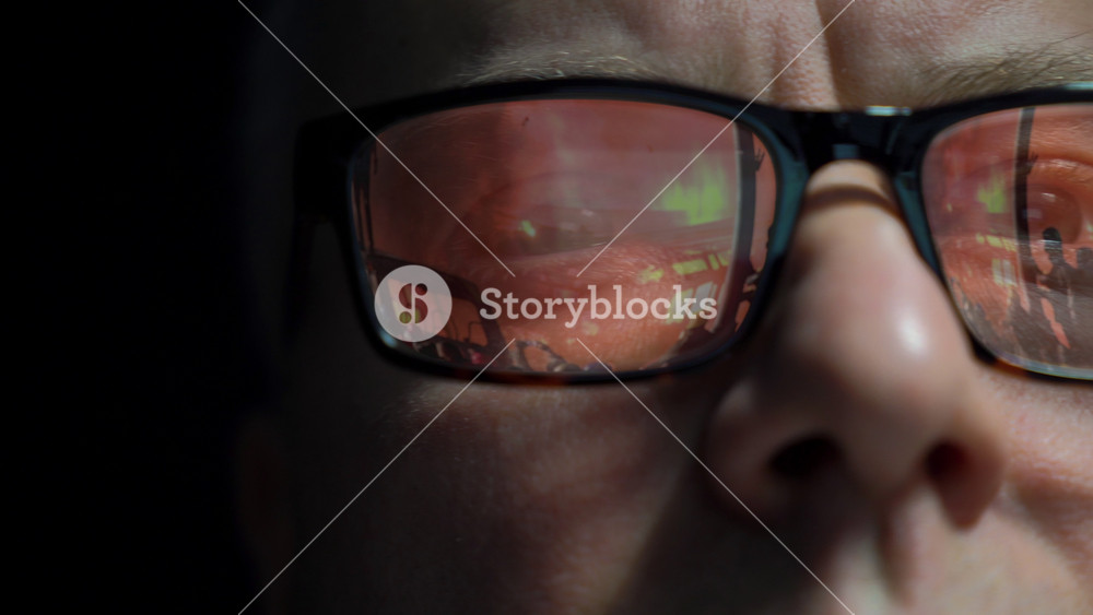A middle-aged man watches shocking world news. Pictures of wars, fires, catastrophes are reflected in his The influence of the media on the