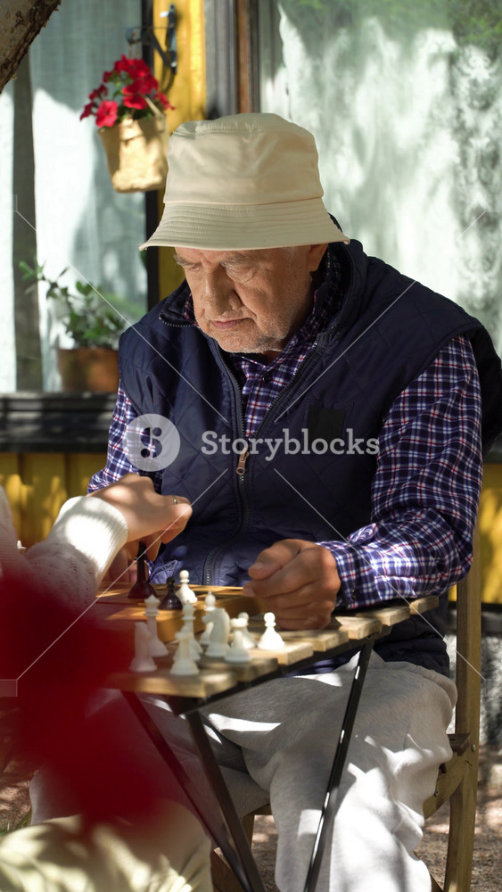 Senior man and young woman playing chess in the garden. Leisure activity, mental health and full life in old age, sport, entertainment, old
